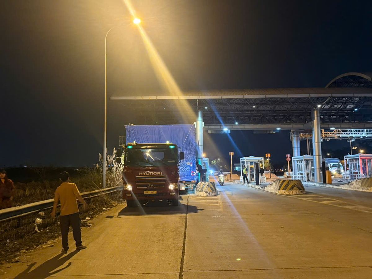 Xe dẫn đường đưa tổ hợp chở kiện hàng siêu trường qua làn mở rộng trạm thu phí ban đêm