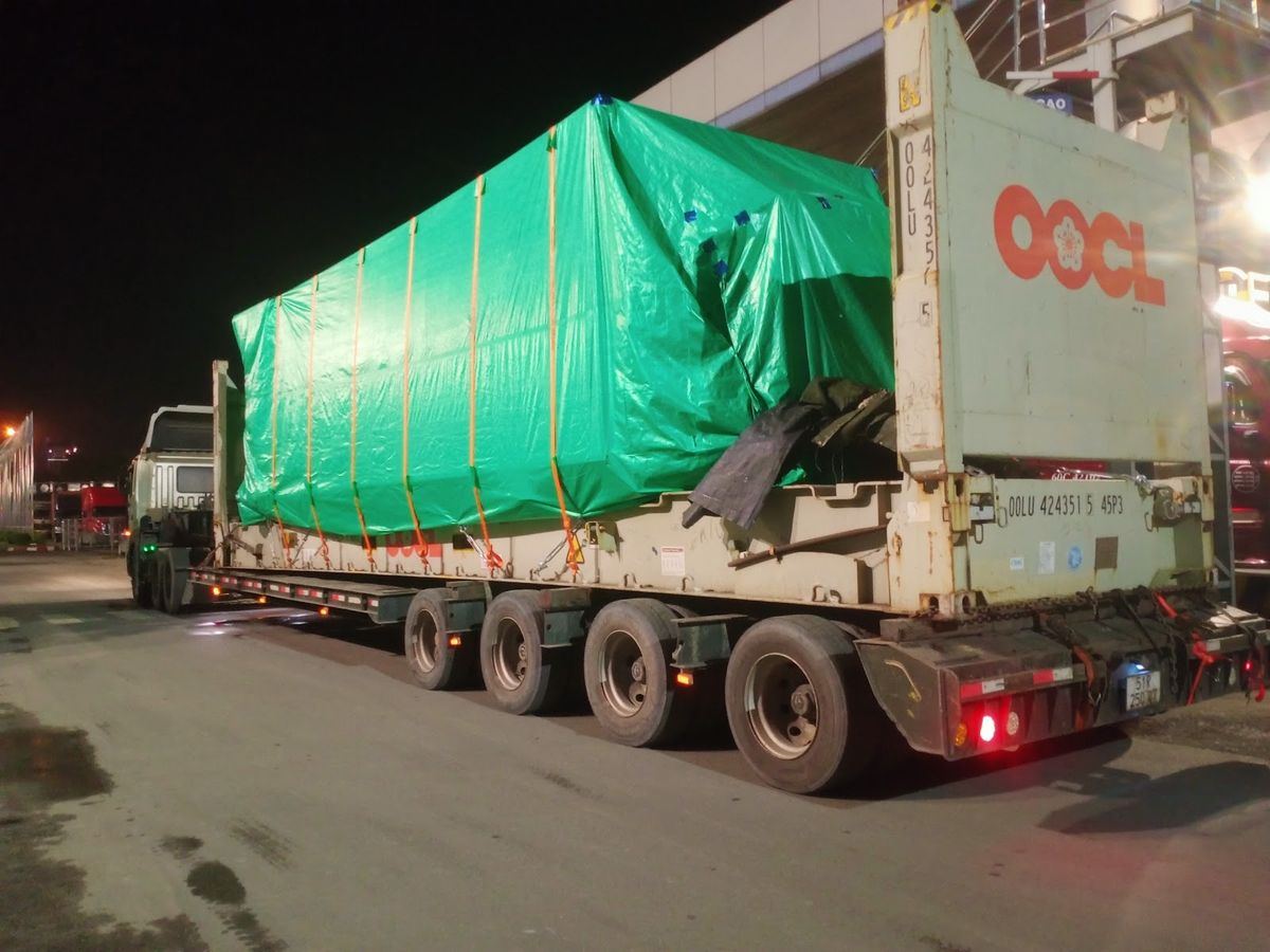 Máy móc quá khổ được bọc bạt lashing chắc chắn trên sàn Flat Rack