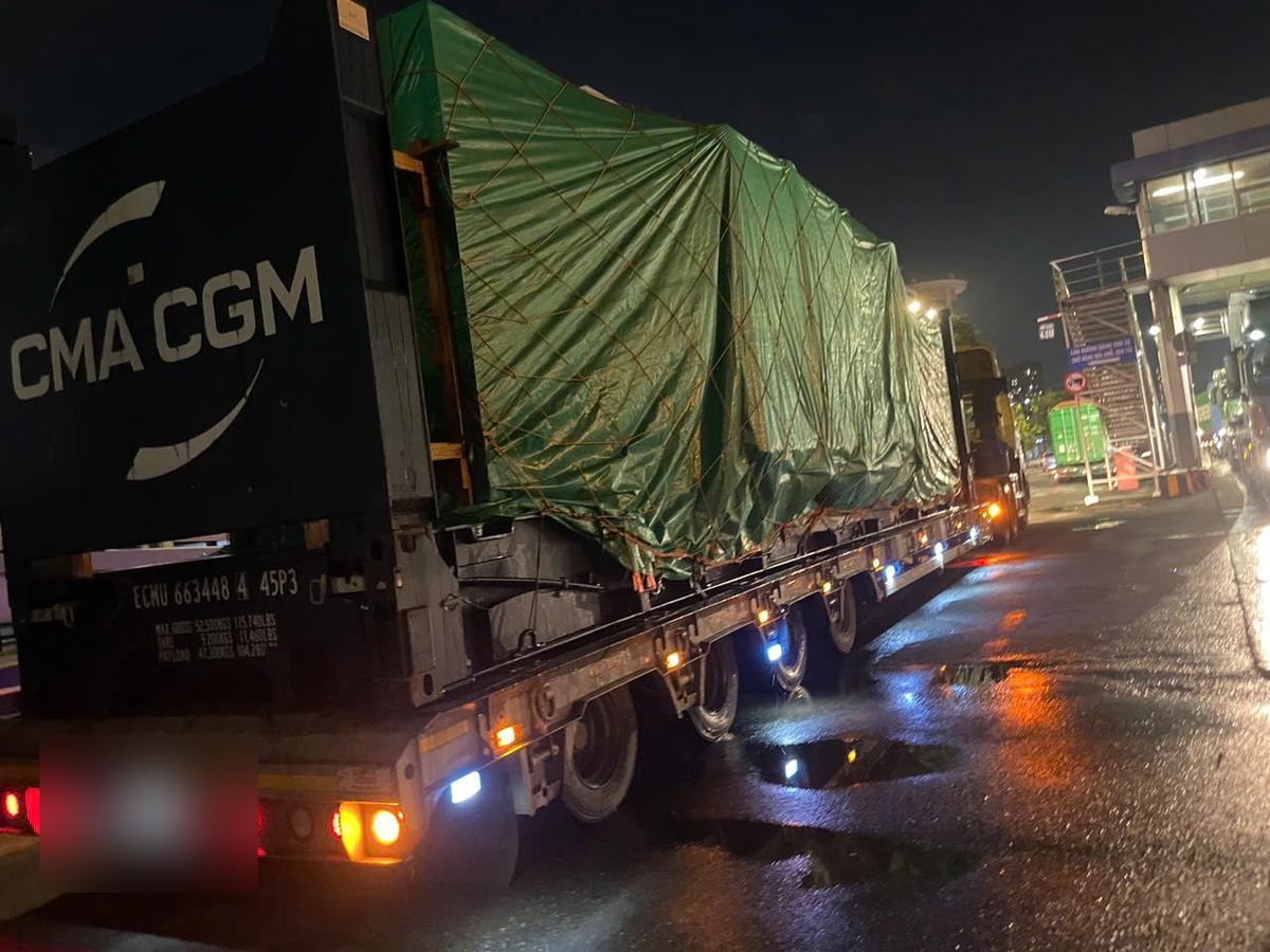 Covered machinery on a 40ft flat rack on a multi-axle trailer leaving Cat Lai port at night