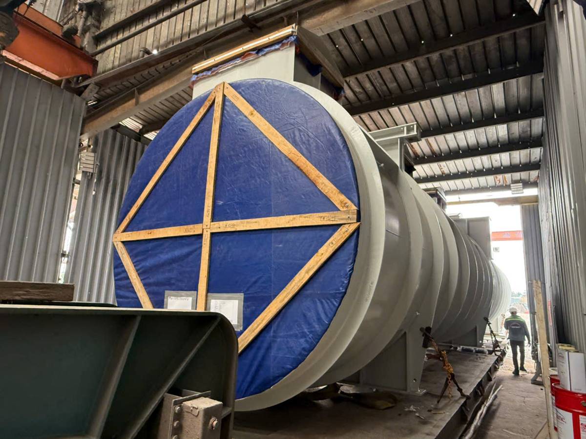 Cylindrical breakbulk package covered and lashed on a trailer at a Binh Chanh workshop before trucking to Gemalink