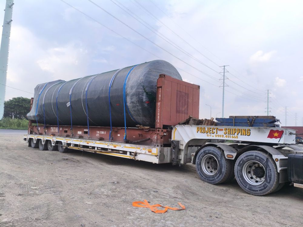 Heavy haulage in Vietnam: large tank on a 40' flat rack carried by a Project Shipping lowbed after discharge at Cat Lai port