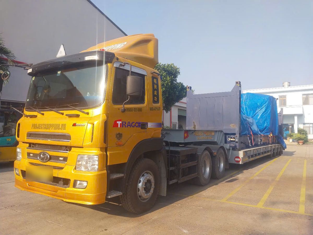 Imported flat rack covered with blue tarpaulin on a Project Shipping truck at the receiver's yard