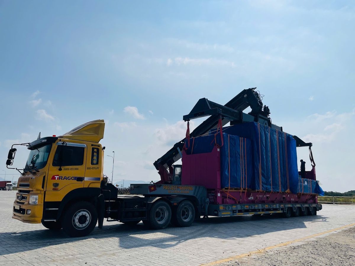 Reach stacker loading a 40ft flat rack with project cargo onto a Project Shipping lowbed at Cai Mep