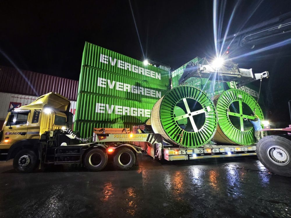 Six cable reels on open top containers carried on two Project Shipping lowbeds at night