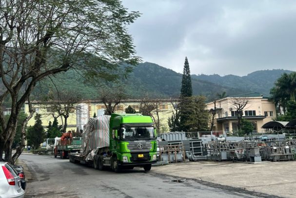 Truck with a tarped transformer body leaving the factory in Cam Pha for the substation