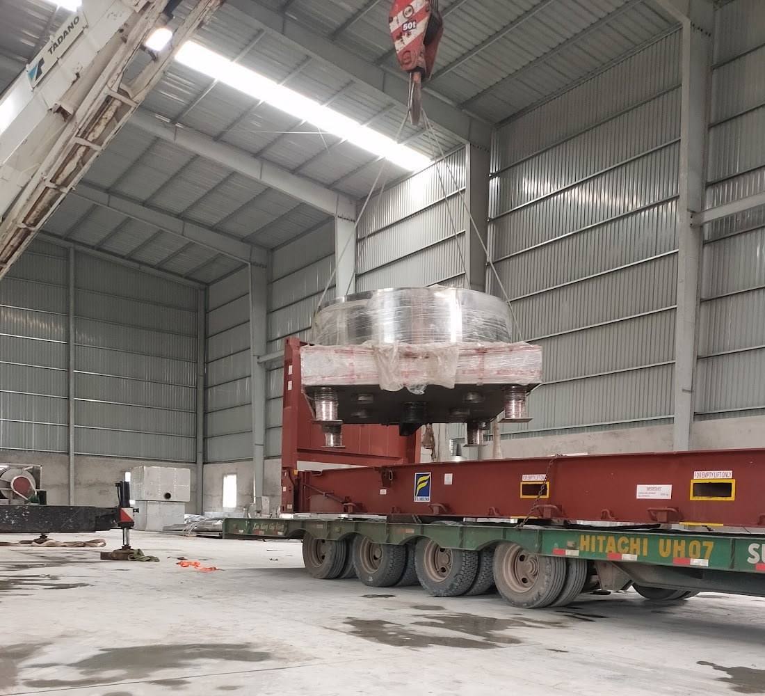 cẩu dỡ khối inox tròn khỏi Flat Rack trong nhà xưởng